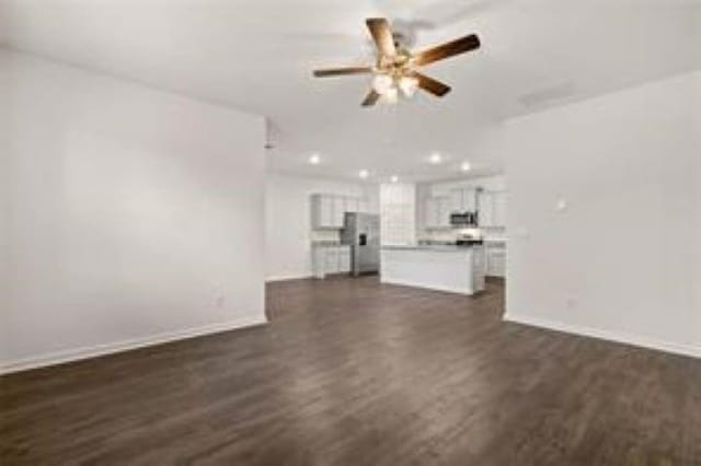 unfurnished living room with baseboards, ceiling fan, and dark wood-style flooring