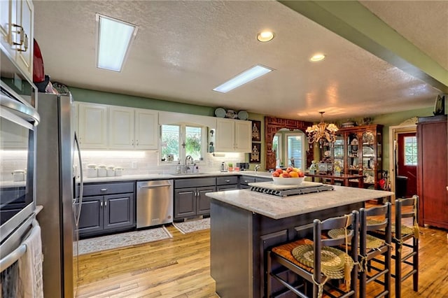 476 Franklin St, Dillard, GA 30537 - kitchen with stainless steel appliances, gray cabinetry, a textured ceiling, light wood finished floors, and a breakfast bar