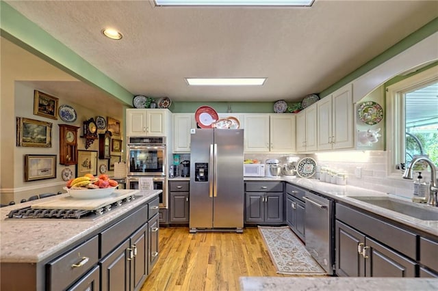 476 Franklin St, Dillard, GA 30537 - kitchen with appliances with stainless steel finishes, gray cabinets, white cabinets, light wood-style flooring, and backsplash