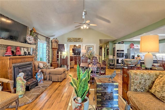 476 Franklin St, Dillard, GA 30537 - living area with a ceiling fan, vaulted ceiling, light wood-type flooring, and a fireplace with raised hearth