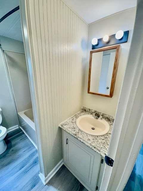 bathroom featuring tub / shower combination, wood finished floors, toilet, and vanity