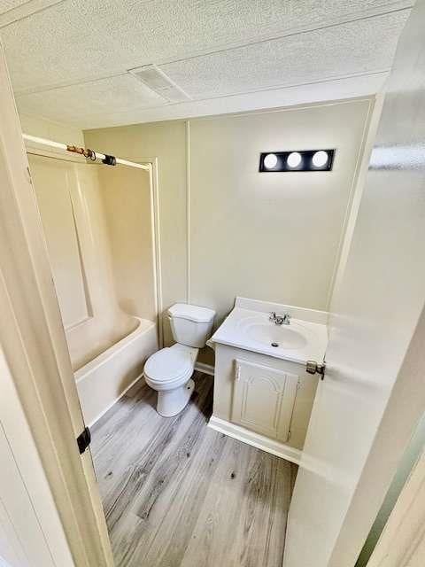 full bathroom with vanity, toilet, a textured ceiling, shower / washtub combination, and wood finished floors