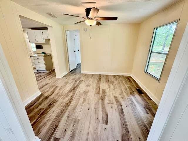 spare room featuring baseboards, visible vents, a ceiling fan, and light wood finished floors