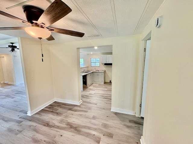 interior space with light wood-style floors, a ceiling fan, and baseboards