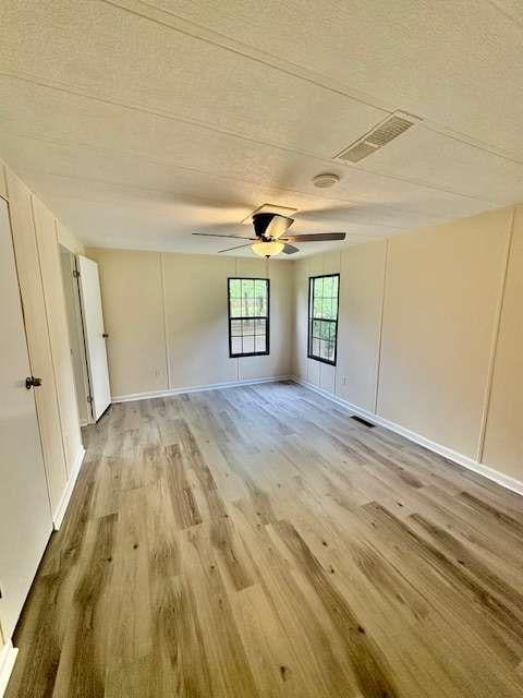 spare room featuring a textured ceiling, visible vents, ceiling fan, and light wood-type flooring