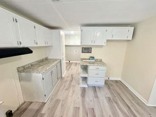 kitchen with white cabinetry, open shelves, light wood-style flooring, baseboards, and light stone countertops