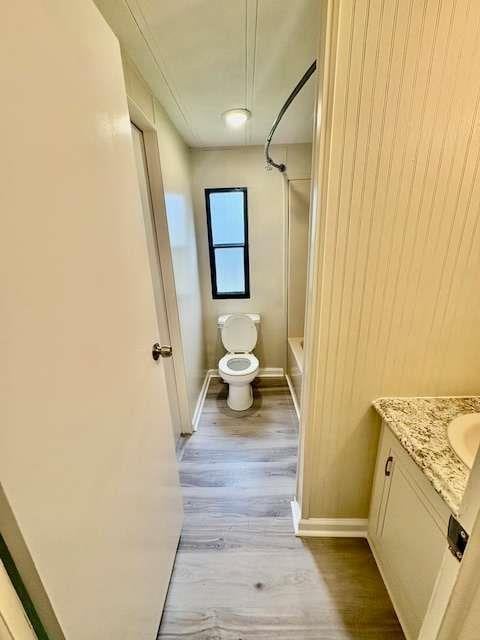 full bath with vanity, toilet, bathtub / shower combination, baseboards, and wood finished floors