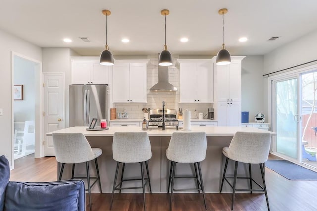 kitchen featuring decorative light fixtures, an island with sink, white cabinets, and appliances with stainless steel finishes