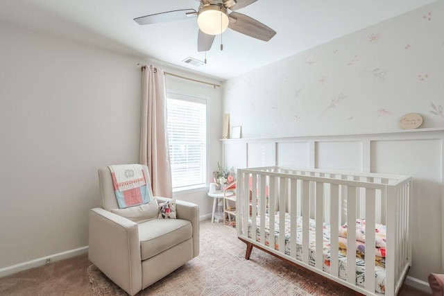 bedroom with a crib, ceiling fan, and carpet