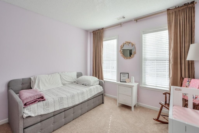 carpeted bedroom featuring multiple windows and a textured ceiling