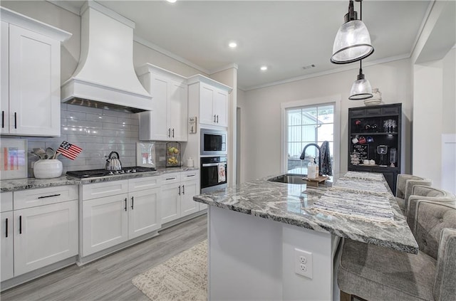884 Oxford Rd, Ball Ground, GA 30107 - kitchen with custom range hood, appliances with stainless steel finishes, light wood finished floors, ornamental molding, and white cabinetry