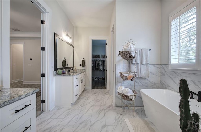 884 Oxford Rd, Ball Ground, GA 30107 - bathroom with vanity, a freestanding bath, marble look tiles, and a spacious closet