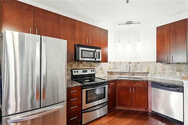 kitchen with dark stone countertops, a sink, backsplash, and stainless steel appliances