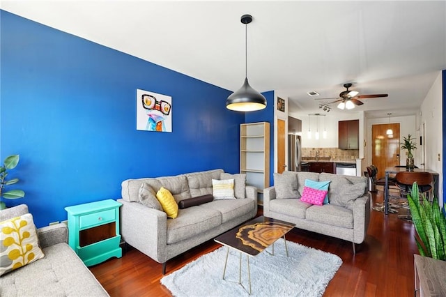 living room with visible vents, wood finished floors, and a ceiling fan