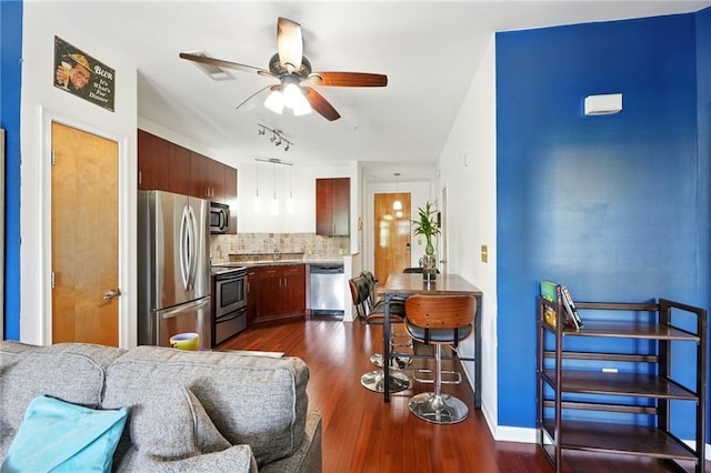 kitchen featuring appliances with stainless steel finishes, backsplash, dark wood-style flooring, pendant lighting, and a ceiling fan