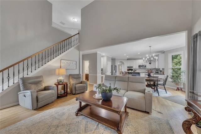 809 Hillcrest Ln, Woodstock, GA 30189 - living room with a chandelier, stairs, light wood finished floors, baseboards, and a towering ceiling