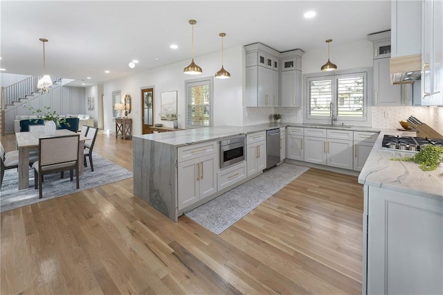 3899 Carlton Dr, Chamblee, GA 30341 - kitchen featuring stainless steel appliances, a peninsula, decorative backsplash, light stone counters, and light wood-style flooring