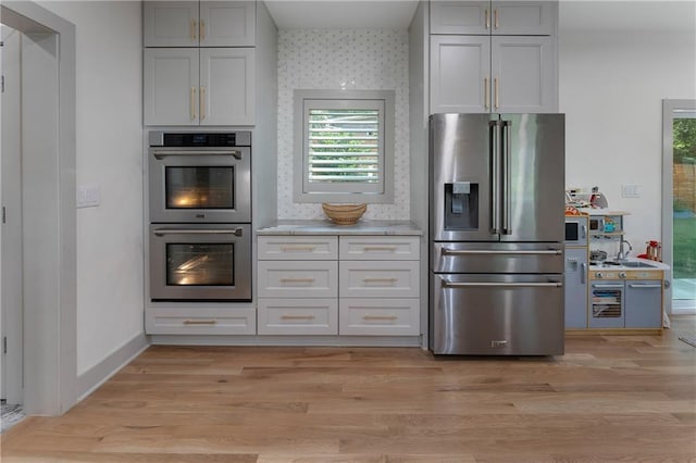3899 Carlton Dr, Chamblee, GA 30341 - kitchen featuring appliances with stainless steel finishes, wallpapered walls, light wood-style flooring, and healthy amount of natural light