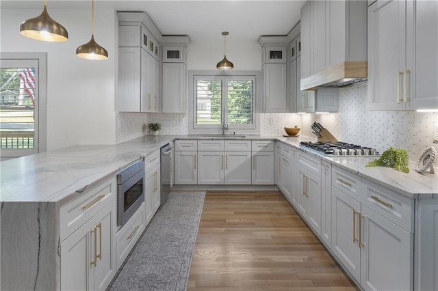 3899 Carlton Dr, Chamblee, GA 30341 - kitchen featuring appliances with stainless steel finishes, a peninsula, light wood-style flooring, custom range hood, and glass insert cabinets