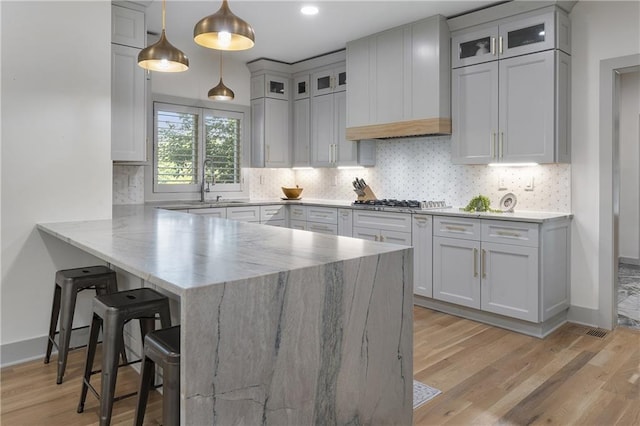 3899 Carlton Dr, Chamblee, GA 30341 - kitchen featuring a peninsula, a kitchen breakfast bar, light stone countertops, light wood finished floors, and tasteful backsplash