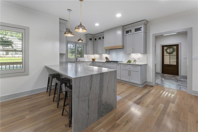 3899 Carlton Dr, Chamblee, GA 30341 - kitchen with a kitchen breakfast bar, a peninsula, light wood-type flooring, glass insert cabinets, and tasteful backsplash