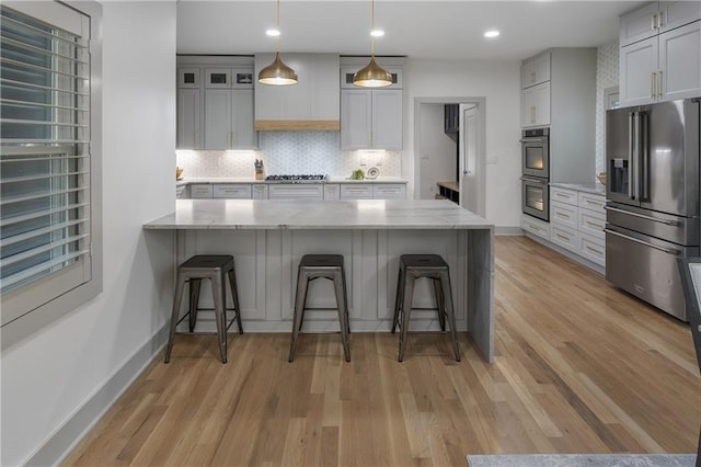 3899 Carlton Dr, Chamblee, GA 30341 - kitchen featuring appliances with stainless steel finishes, light wood-type flooring, light stone countertops, decorative backsplash, and a kitchen breakfast bar