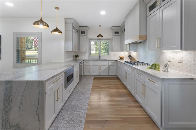 3899 Carlton Dr, Chamblee, GA 30341 - kitchen featuring a peninsula, appliances with stainless steel finishes, light wood-type flooring, glass insert cabinets, and custom range hood