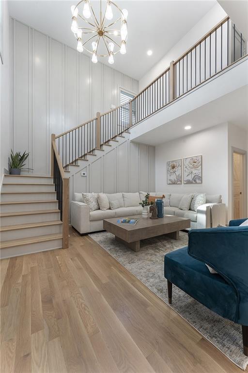 3899 Carlton Dr, Chamblee, GA 30341 - living room featuring a decorative wall, stairway, wood finished floors, a chandelier, and a high ceiling