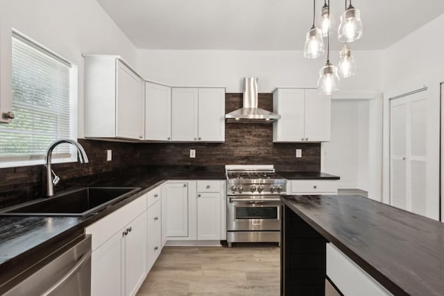 kitchen featuring sink, white cabinets, wall chimney range hood, and appliances with stainless steel finishes