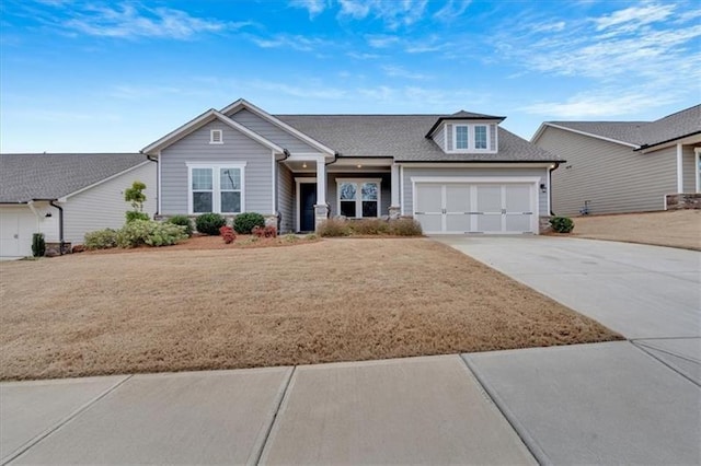 craftsman-style home with driveway, a shingled roof, and a garage