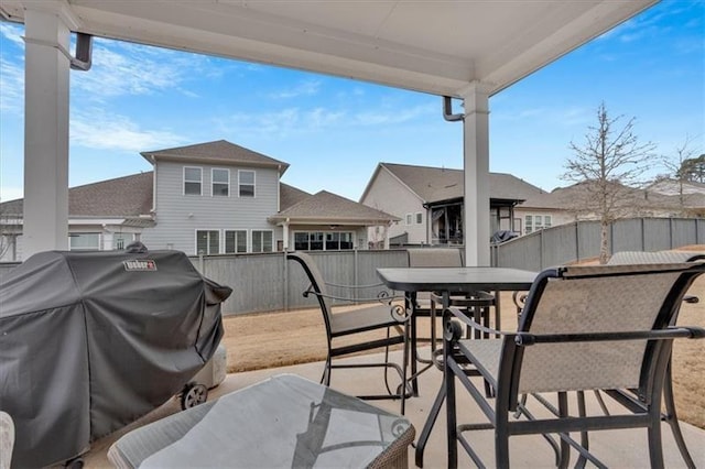 view of patio featuring fence, grilling area, a residential view, and outdoor dining area