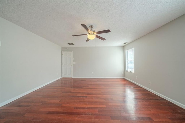 empty room featuring a textured ceiling, wood finished floors, visible vents, and baseboards