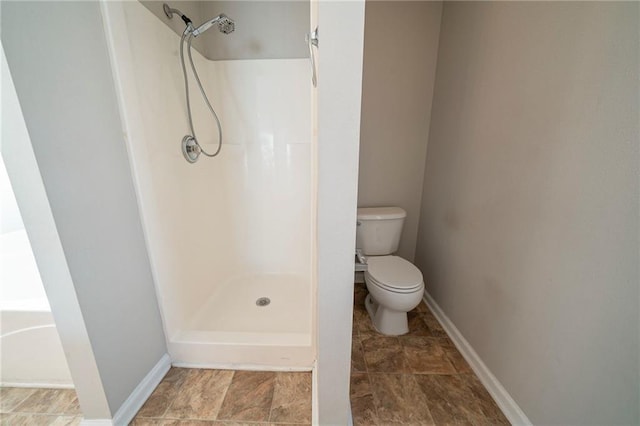 bathroom featuring a walk in shower, toilet, and baseboards