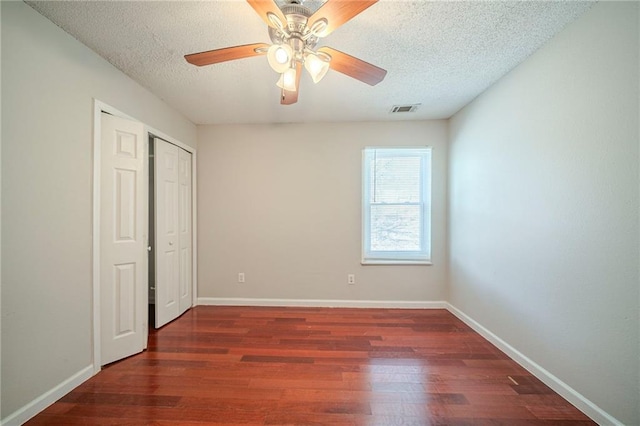 unfurnished bedroom featuring visible vents, a textured ceiling, baseboards, and wood finished floors