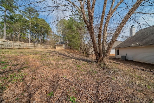 view of yard featuring central air condition unit, a shed, fence, and an outdoor structure