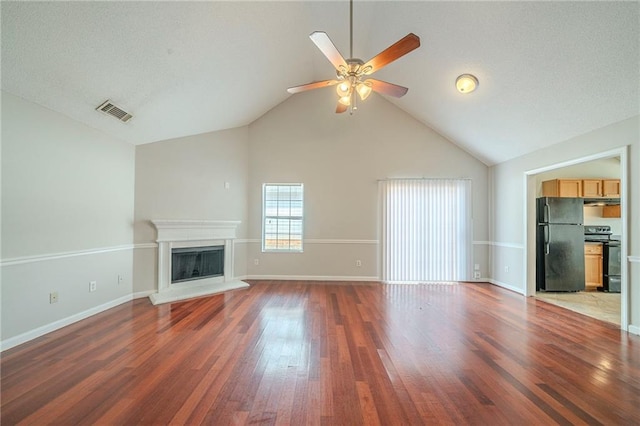 unfurnished living room with visible vents, a fireplace with raised hearth, baseboards, and wood finished floors