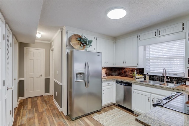 kitchen with sink, light hardwood / wood-style flooring, white cabinetry, backsplash, and stainless steel appliances