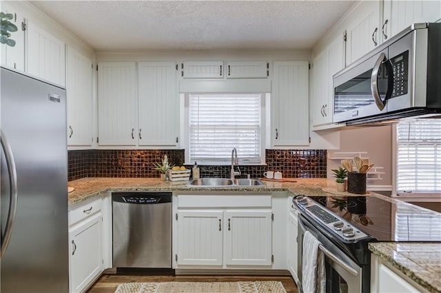 kitchen featuring white cabinetry, stainless steel appliances, light stone countertops, and sink