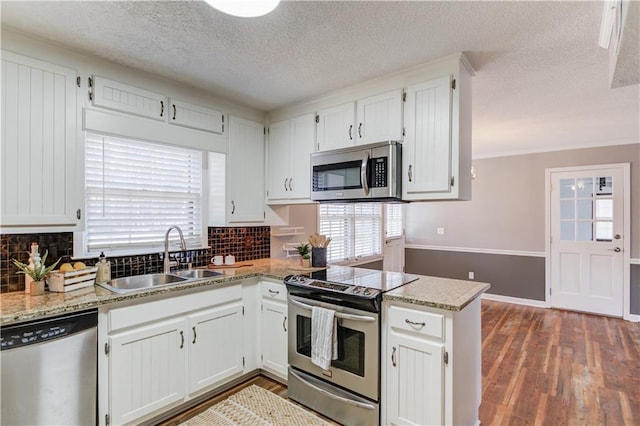 kitchen with stainless steel appliances, white cabinetry, sink, and kitchen peninsula