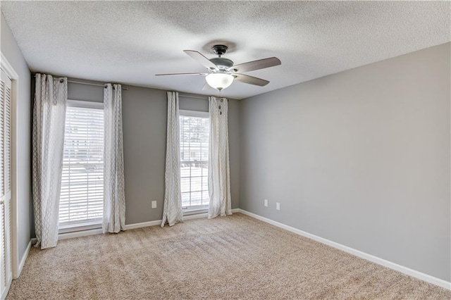 spare room with a textured ceiling, light colored carpet, and ceiling fan