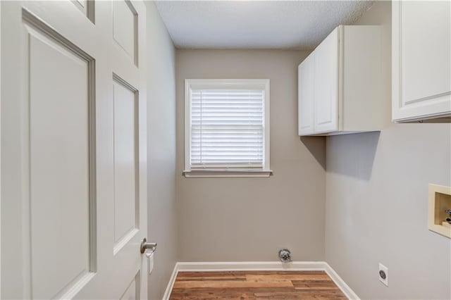 clothes washing area with light wood-type flooring, cabinets, washer hookup, hookup for an electric dryer, and a textured ceiling