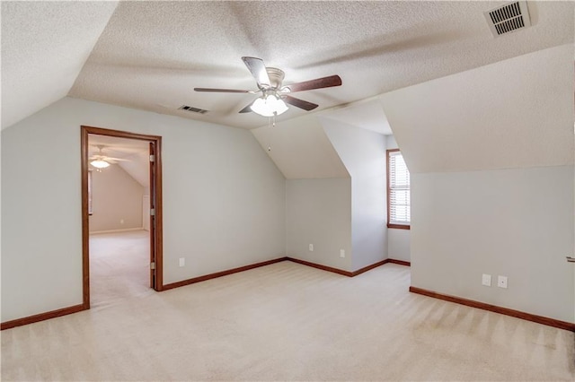 bonus room featuring ceiling fan, lofted ceiling, light carpet, and a textured ceiling