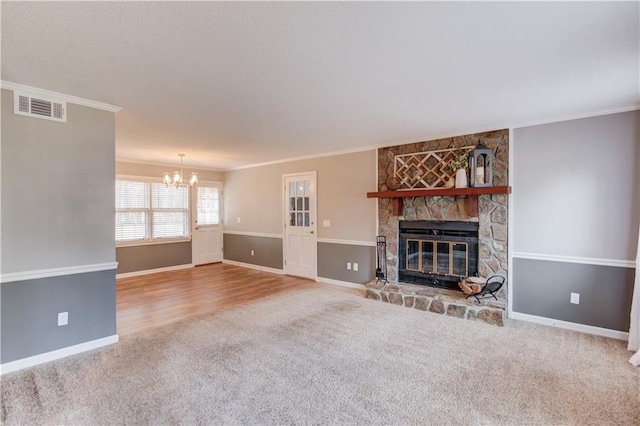 unfurnished living room with crown molding, a stone fireplace, carpet, and an inviting chandelier