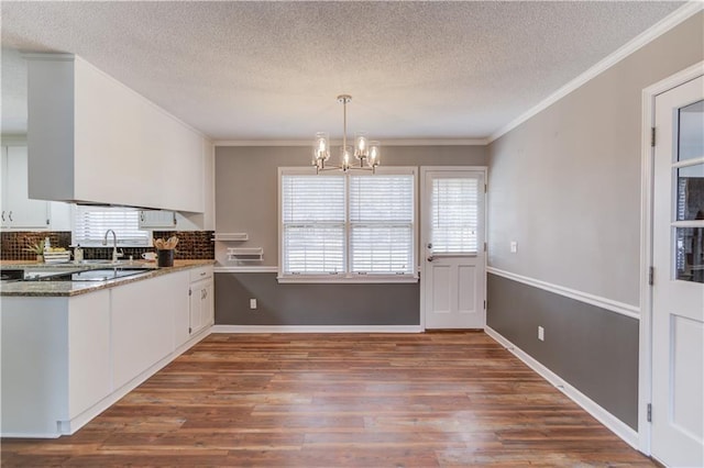 kitchen featuring pendant lighting, crown molding, hardwood / wood-style floors, and white cabinets