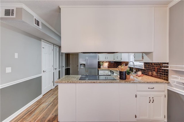 kitchen with white cabinets, ornamental molding, light stone counters, stainless steel refrigerator with ice dispenser, and light hardwood / wood-style flooring