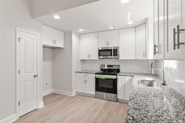 5209 Waterworks Rd, Jefferson, GA 30549 - kitchen with stainless steel appliances, light stone counters, a sink, white cabinets, and light wood-style flooring