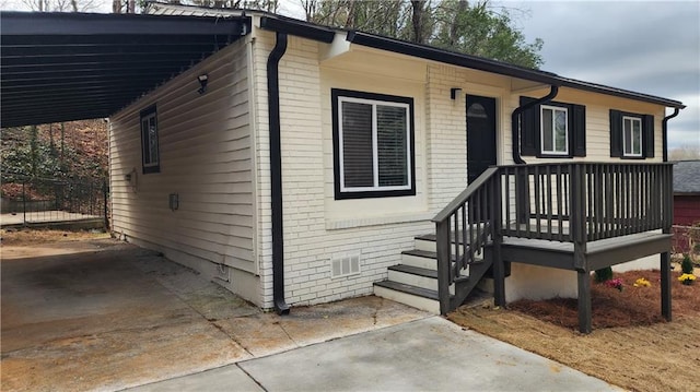 view of front of house featuring concrete driveway, an attached carport, crawl space, fence, and brick siding