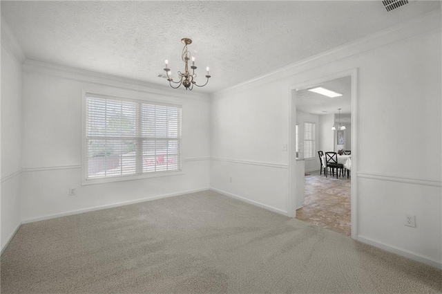 carpeted spare room featuring a chandelier, crown molding, baseboards, and a textured ceiling