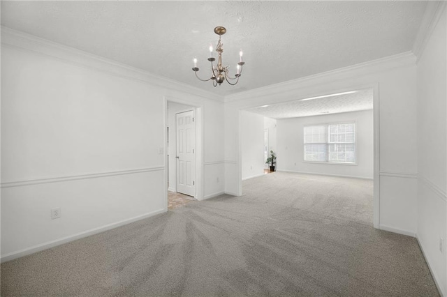 empty room with a textured ceiling, ornamental molding, carpet floors, a notable chandelier, and baseboards