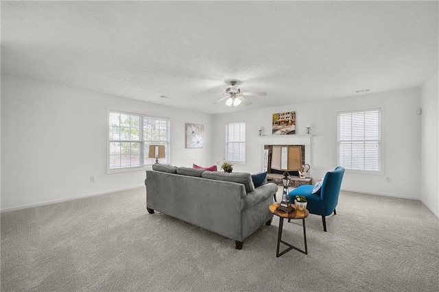 living room with baseboards, a ceiling fan, a fireplace, a textured ceiling, and carpet flooring